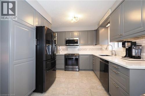 Kitchen featuring extensive grey cabinetry, stainless steel appliances, light-toned countertops, a subway tile backsplash, and neutral tile flooring - 70 Queen Charlotte Crescent, Kitchener, ON - Indoor Photo Showing Kitchen With Upgraded Kitchen