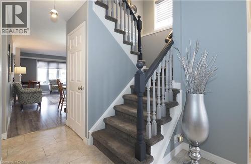 Foyer featuring tile flooring, a carpeted staircase with painted wood newel posts and spindles, and a white six-panel door - 70 Queen Charlotte Crescent, Kitchener, ON - Indoor Photo Showing Other Room