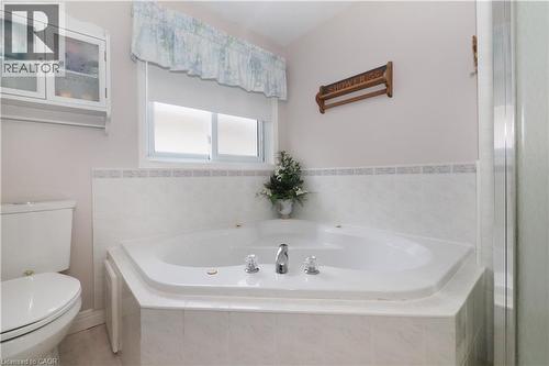 Corner jetted tub with tiled surround, chrome fixtures, and a privacy window - 70 Queen Charlotte Crescent, Kitchener, ON - Indoor Photo Showing Bathroom