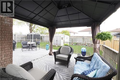 Covered outdoor patio area featuring a dark metal gazebo, brick exterior wall, and wooden deck flooring - 70 Queen Charlotte Crescent, Kitchener, ON - Outdoor With Deck Patio Veranda With Exterior