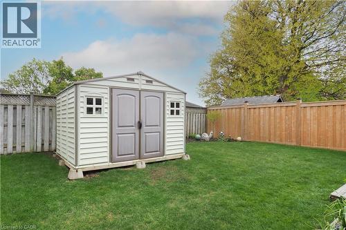 Expansive backyard featuring a manicured lawn, a white storage shed with double doors and window details, a stained wood privacy fence, and mature trees - 70 Queen Charlotte Crescent, Kitchener, ON - Outdoor