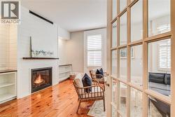 Living area featuring a fireplace with a wood mantle, built-in shelving, wood-finish flooring, and shuttered windows - 