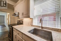 Kitchen featuring a stainless steel sink with a gooseneck faucet, white cabinetry, speckled countertops, and a white subway tile backsplash - 