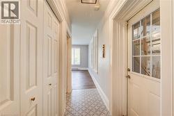 Hallway featuring patterned tile flooring, wood-finish flooring, white panel doors, and a glass-paneled exterior door - 