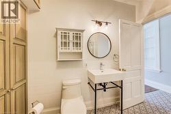 Bathroom featuring a pedestal sink, round mirror, and patterned tile flooring - 
