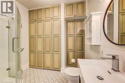 Bathroom featuring extensive built-in cabinetry and a glass-enclosed shower - 