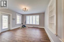 Spacious room featuring wood-finish flooring, light grey walls, and white trim - 