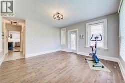Spacious interior room featuring wood-finish flooring, light gray wall tones, and white trim - 