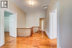 Hallway featuring wood-finish flooring, white trim, and a wood banister - 