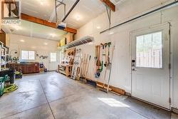 Spacious garage featuring a concrete floor, exposed wood beams, multiple windows for natural light, and a built-in workbench area - 
