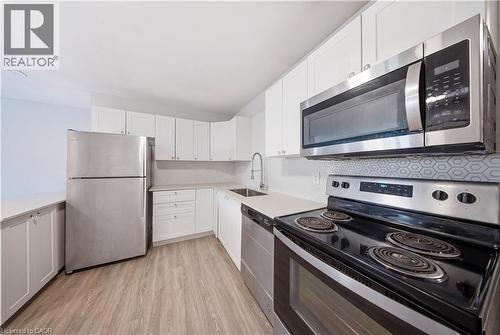 Kitchen featuring white cabinetry, light-toned countertops, and wood-finish flooring - 91 Westmount Road Unit# 3, Waterloo, ON - Indoor Photo Showing Kitchen With Stainless Steel Kitchen