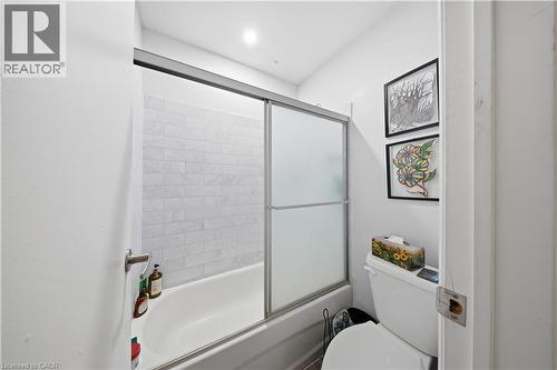 Full bathtub with subway tile surround and sliding frosted glass shower doors - 91 Westmount Road Unit# 3, Waterloo, ON - Indoor Photo Showing Bathroom