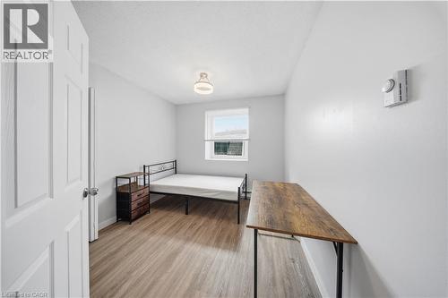 Bedroom featuring wood-finish flooring, a window providing natural light, a ceiling-mounted light fixture, and a wall-mounted control unit - 91 Westmount Road Unit# 3, Waterloo, ON - Indoor Photo Showing Other Room