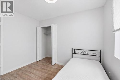 Light wood-finish flooring, white walls, and a bi-fold closet with shelving and a hanging rod - 91 Westmount Road Unit# 3, Waterloo, ON - Indoor