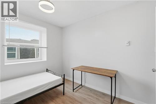 Bright room featuring wood-finish flooring, a contemporary ceiling light fixture, a window with blinds, and white walls - 91 Westmount Road Unit# 3, Waterloo, ON - Indoor