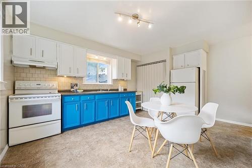 Open-concept kitchen featuring two-tone cabinetry, white appliances, a tile backsplash, and track lighting - 87 Barbara Crescent, Kitchener, ON - Indoor