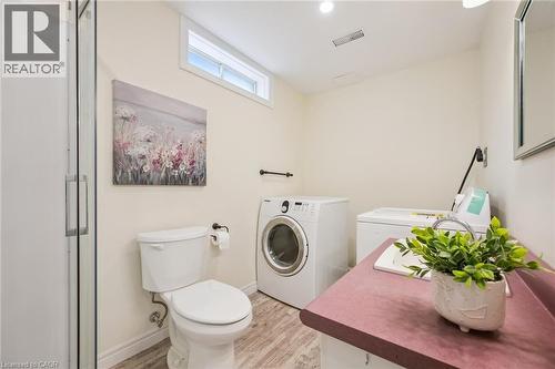 Utility room featuring a glass shower enclosure, white toilet, and wood-finish flooring - 87 Barbara Crescent, Kitchener, ON - Indoor Photo Showing Laundry Room
