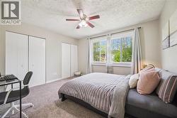 Bedroom featuring multiple bi-fold door closets, a ceiling fan with integrated lighting, and a large window with white trim - 