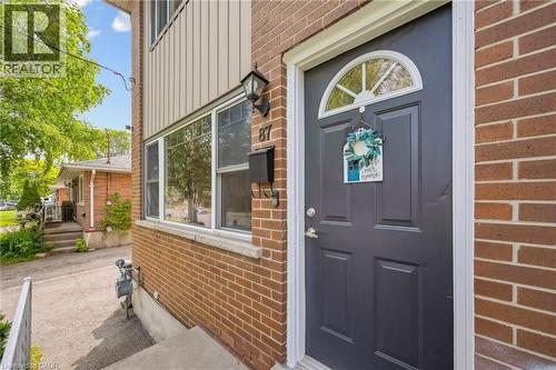 Brick exterior featuring a paneled front door with an arched transom, exterior wall lantern, and multiple windows with white trim - 87 Barbara Crescent, Kitchener, ON - Outdoor With Exterior