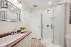 Bathroom featuring a corner glass-enclosed shower, single vanity with a built-in sink, and a framed mirror with overhead lighting - 