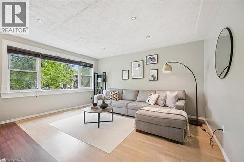 Spacious living area featuring light wood-finish flooring, a tray ceiling with recessed lighting, and a large multi-pane window with white trim - 87 Barbara Crescent, Kitchener, ON - Indoor Photo Showing Living Room