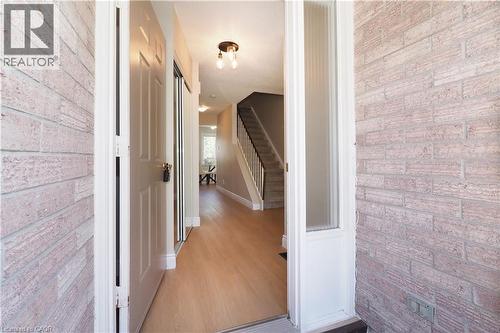 Foyer entry featuring light wood-finish flooring, a contemporary ceiling light fixture, a sidelight window, a paneled entry door, and a staircase with dark handrails - 27 Scenic Wood Crescent, Kitchener, ON - Indoor Photo Showing Other Room