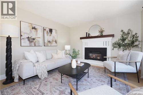 Living area featuring a white brick fireplace with a dark wood mantel, light-toned walls, and wood-finish flooring - 27 Scenic Wood Crescent, Kitchener, ON - Indoor Photo Showing Living Room With Fireplace