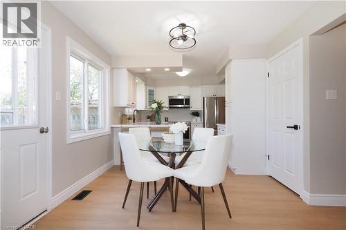 Open-concept kitchen and dining area featuring light wood-finish flooring, white cabinetry, stainless steel appliances, and a glass-paneled exterior door - 27 Scenic Wood Crescent, Kitchener, ON - Indoor Photo Showing Dining Room