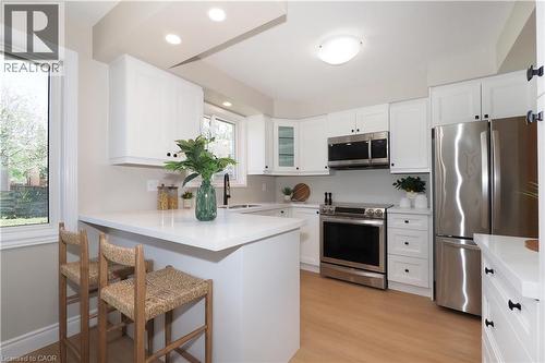 Modern kitchen featuring white cabinetry, stainless steel appliances, a quartz countertop island with seating, recessed lighting, and wood-finish flooring - 27 Scenic Wood Crescent, Kitchener, ON - Indoor Photo Showing Kitchen
