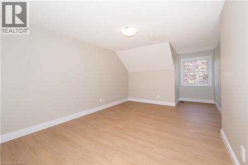 Spacious room featuring light wood-finish flooring, neutral wall paint, a white-framed window, and a flush-mount ceiling light fixture - 27 Scenic Wood Crescent, Kitchener, ON - Indoor Photo Showing Other Room