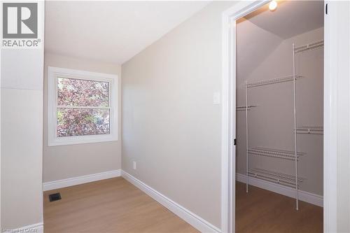 Room featuring wood-finish flooring, a window with exterior foliage, and white baseboards - 27 Scenic Wood Crescent, Kitchener, ON - Indoor Photo Showing Other Room