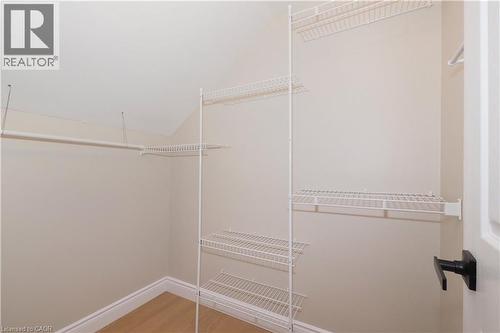 Walk-in closet with wire shelving system, hanging rod, neutral wall paint, white trim, and wood-finish flooring - 27 Scenic Wood Crescent, Kitchener, ON - Indoor With Storage