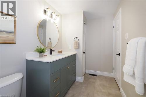 Modern bathroom featuring a deep green vanity with gold-tone hardware, a white countertop, and a round gold-framed mirror - 27 Scenic Wood Crescent, Kitchener, ON - Indoor Photo Showing Bathroom