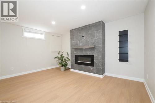 Modern electric fireplace with a stone-look tile surround and wood mantel - 27 Scenic Wood Crescent, Kitchener, ON - Indoor With Fireplace