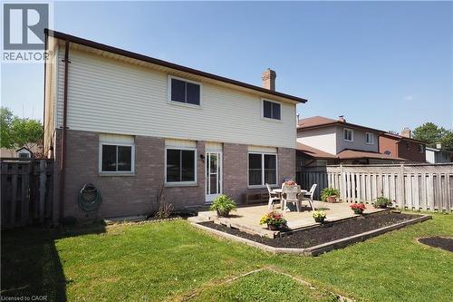 Rear exterior showcasing a ground-level wood-finish deck with a mulched garden bed surround - 27 Scenic Wood Crescent, Kitchener, ON - Outdoor