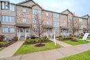 Brick and siding townhome exterior featuring multiple windows, individual covered entryways with white railings, a concrete walkway, and manicured landscaping with young trees - 275 Old Huron Road Unit# 21, Kitchener, ON  - Outdoor With Facade 