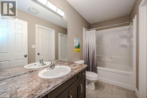 Bathroom featuring a double vanity with integrated sinks, a patterned countertop, dark wood-finish cabinetry, and a full-size bathtub with an overhead shower - 275 Old Huron Road Unit# 21, Kitchener, ON - Indoor Photo Showing Bathroom