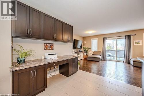Built-in desk area featuring dark wood-finish cabinetry, a stone-look countertop, and overhead storage - 275 Old Huron Road Unit# 21, Kitchener, ON - Indoor