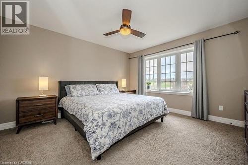 Carpeted room featuring a ceiling fan with integrated lighting, a large window with grid panes, and neutral wall tones - 275 Old Huron Road Unit# 21, Kitchener, ON - Indoor Photo Showing Bedroom
