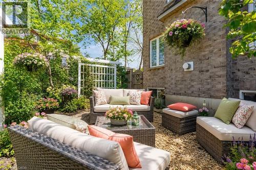 Backyard private outdoor patio featuring a gravel surface and lush landscaping, enjoy all summer long (cushions and flowers are virtual staged) - 16 Westridge Drive, Hamilton, ON - Outdoor With Deck Patio Veranda