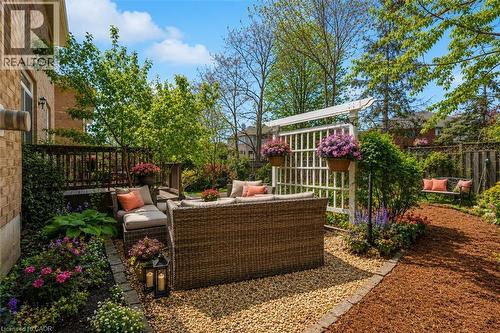 Backyard private outdoor patio featuring a gravel surface and lush landscaping, enjoy all summer long (cushions and flowers are virtual staged) - 16 Westridge Drive, Hamilton, ON - Outdoor
