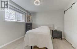 Spacious room featuring light-toned walls, wood-finish flooring, and a large window with blinds - 