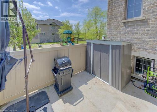 Private concrete patio area featuring a corrugated metal storage shed and a privacy fence - 388 Old Huron Road Unit# 24A, Kitchener, ON - Outdoor With Exterior