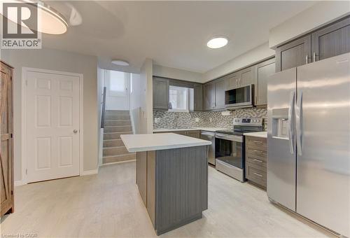 Kitchen with light wood-finish flooring, dark wood-finish cabinetry, stainless steel appliances, and a mosaic tile backsplash - 388 Old Huron Road Unit# 24A, Kitchener, ON - Indoor Photo Showing Kitchen With Upgraded Kitchen