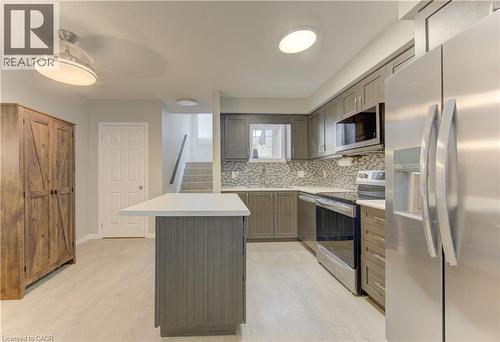 Modern kitchen featuring stainless steel appliances, grey cabinetry, a white countertop island, and wood-finish flooring - 388 Old Huron Road Unit# 24A, Kitchener, ON - Indoor Photo Showing Kitchen With Upgraded Kitchen