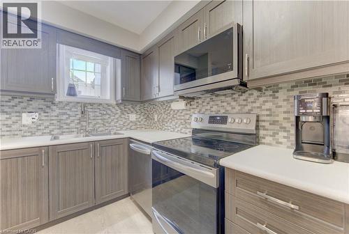 Kitchen featuring light wood-finish cabinetry, a mosaic tile backsplash, white countertops, stainless steel appliances, and a double basin sink with a gooseneck faucet - 388 Old Huron Road Unit# 24A, Kitchener, ON - Indoor Photo Showing Kitchen With Upgraded Kitchen