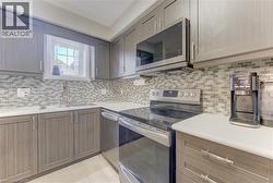 Kitchen featuring light wood-finish cabinetry, a mosaic tile backsplash, white countertops, stainless steel appliances, and a double basin sink with a gooseneck faucet - 