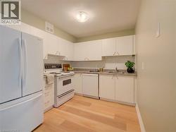Kitchen featuring white cabinetry, wood-finish flooring, subway tile backsplash, and a light-toned countertop - 
