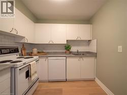 Kitchen featuring white cabinetry, subway tile backsplash, light wood-finish flooring, and a built-in dishwasher - 