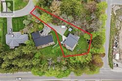 Aerial perspective showcasing a property surrounded by mature trees, featuring a dark shingle roof and an expansive green lawn - 